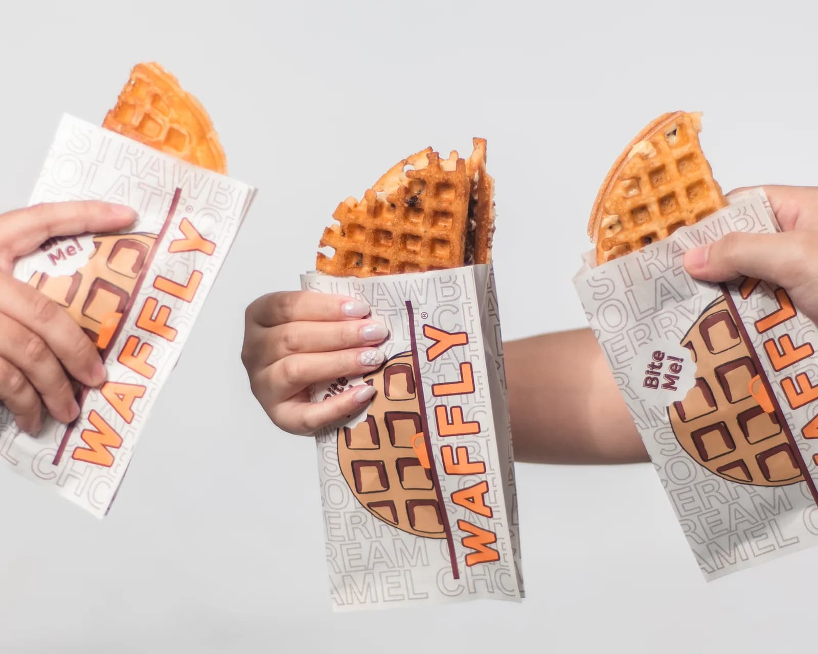 Three Waffly waffles held in their branded sleeves